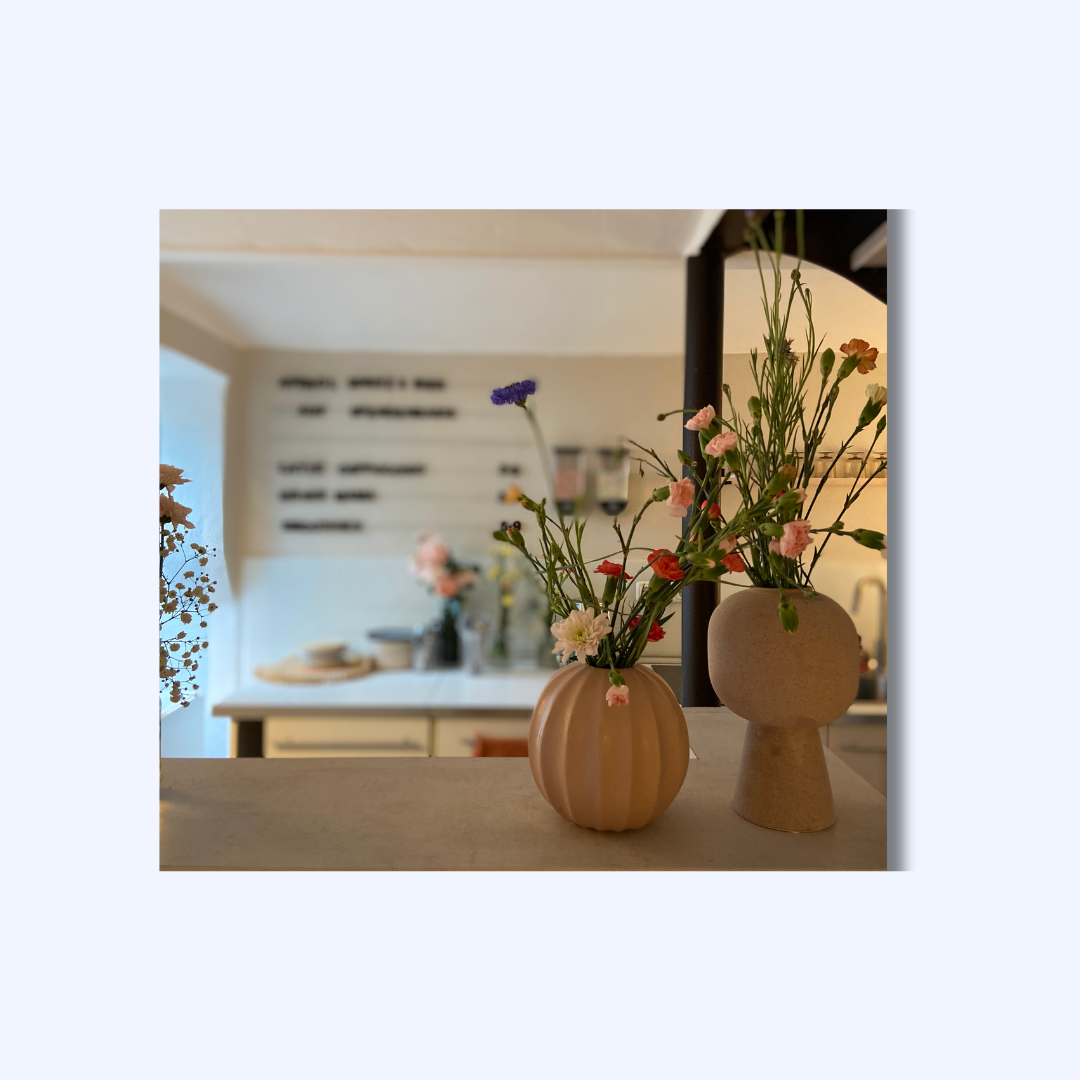 Theke des Studiocafes mit frischen Blumen, im Hintergrund ist die Küche zu sehen